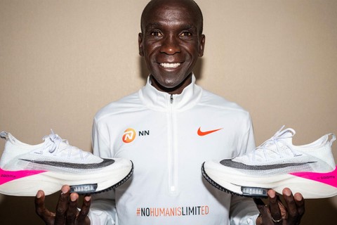 Eliud Kipchoge poses with the record-breaking Nike Vaporfly shoes. [Image credit: ABC News]