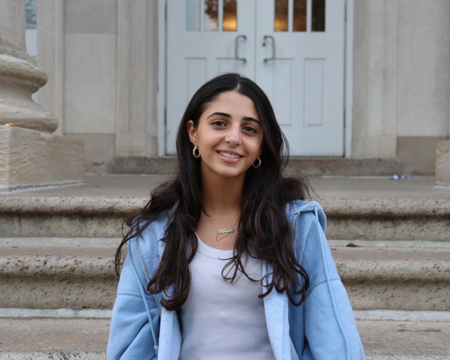 Julia Hakimi sitting on steps leading to the front door of North High